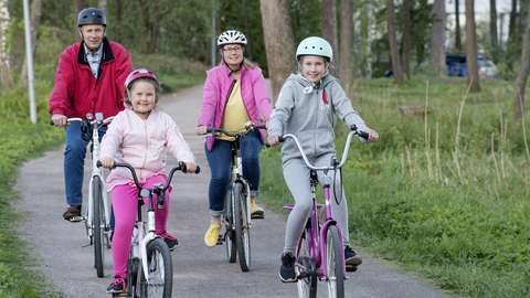 Neljä pyöräilijää pyöräilemässä yhdessä kevyen liikenteen väylällä.