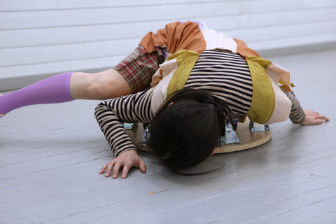 The person is crouched at floor level and leans on the floor with hands.