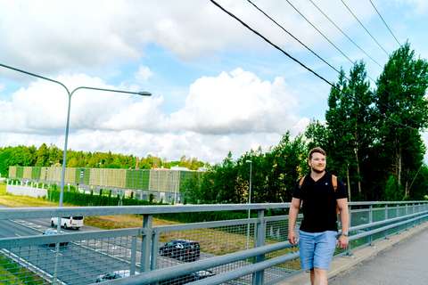 En person går på en övergågsbro, under vilken finns en stor väg. 