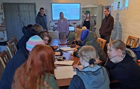 opiskelijat istuvat pöydän ympärillä työskentelemässä