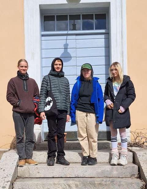 neljä opiskelijaa seisoo rakennuksen rappusilla