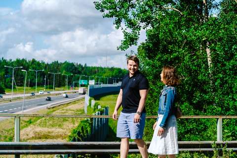 Two people walking on a bridge, under which there is a big road.