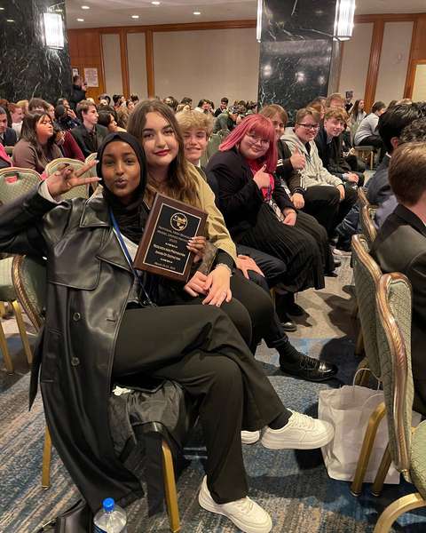 Delegaatit pitelevät palkintoa iloisina.