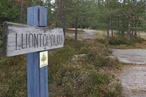 Luontopolkukyltti, joka osoittaa kalliolla jatkuvalle luontopolulle.