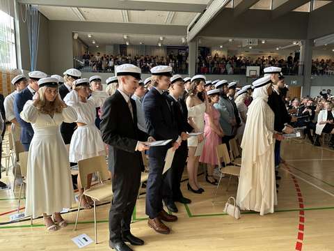 opiskelijat laittavat ylioppilaslakin päähänsä juhlasalissa