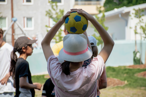 A youngster holds the ball over his/her head outside.