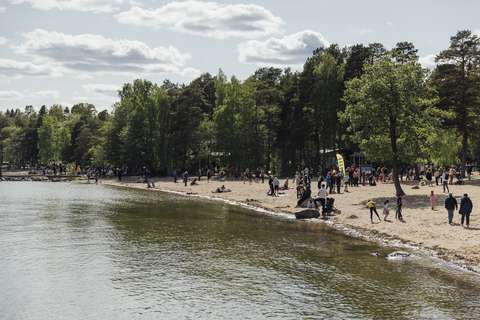 Valokuvassa näkyy uimaranta, jolla on paljon ihmisiä. Sää on aurinkoinen.