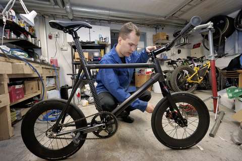 Mies huoltamassa pyöräänsä.