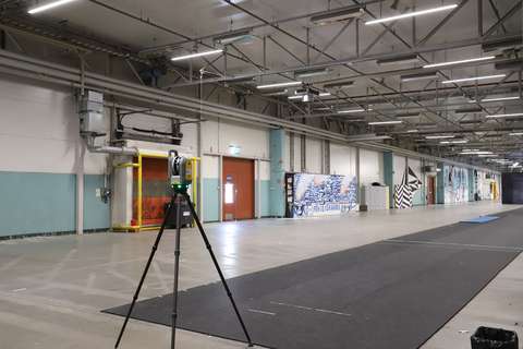 En laserskanningskamera med tre ben står i en bred korridor i den gamla logistikhallen i Kera.