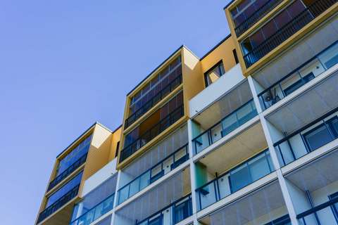 Asuinkerrostalo, jonka takana näkyy pilvetön taivas.