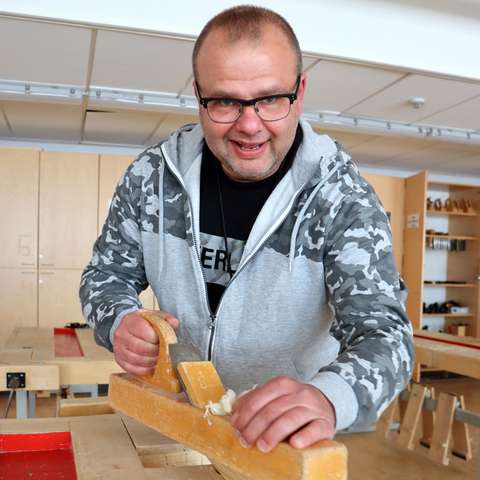 Åke Ryynänen is planing wood in the classroom. 