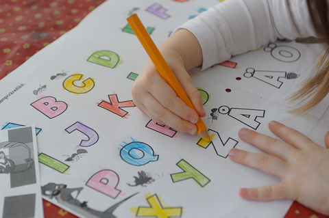 Lapsi värittää kirjaimia.