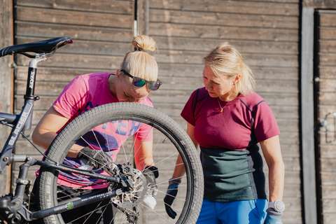 Kaksi naishenkilöä huoltamassa pyörää.