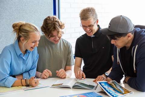 opettaja ja kolme opiskelijaa katsoo kirjaa