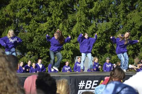 Kuvassa näkyy lava, jolla tanssi neljä teini-ikäistä tyttöä. Kaikilla on päällään farkut ja violetti huppari.
