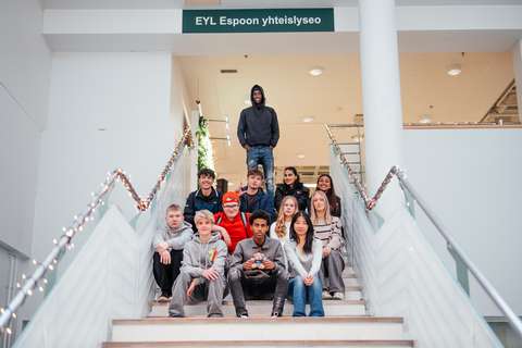 Opiskelijat istuvat portailla nalle sylissä.