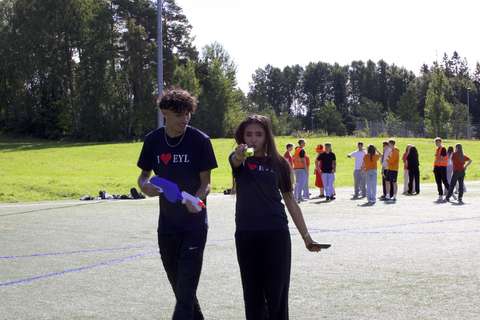 Kuvassa kaksi opiskelijaa tutor-paidat päällä katsoo kameraa. Toisella on kädessääm vesipyssy. 