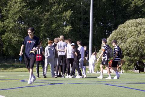 Etualalla Tutor-opiskelija kävelee kohti kameraa ja hänen takanaan ykköset juttelevat pienessä porukassa. 