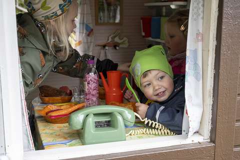 Kolme lasta leikkivät leikkimökissä. 