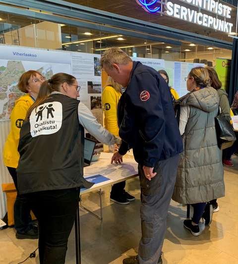 Stadsplaneringscentrets anställda och invånare diskuterar vid plankartan.