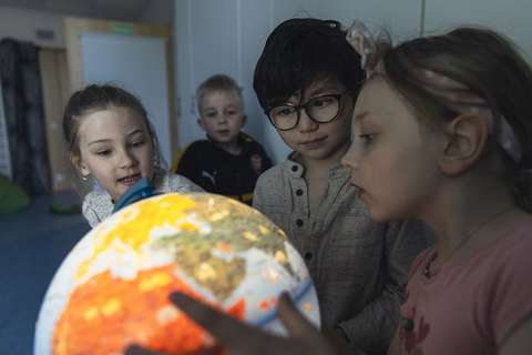 Päiväkotilapset tutkivat karttapalloa yhdessä.