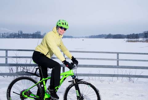 A smiling cyclist in a winter landscape in front of Keilaniemi in Espoo.
