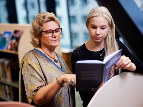 Pirkko Ilmanen and Matilda Levorata reading a book together.