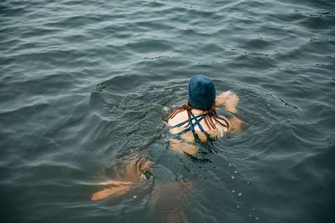 Mirka Törmänen swimming in open water wearing a beanie.