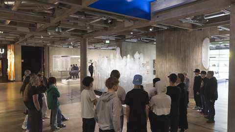 Nuoria kokoontuneena kuuntelemaan opastusta museossa.