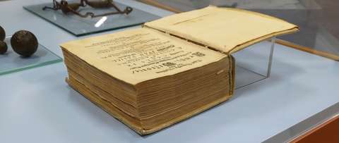 Hyvin vanha paksu kirja avoinna pöydällä.