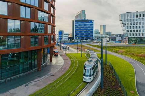  Byggnader, en snabbspårvagn i rörelse och i bakgrunden ändstationen för snabbspårvägslinje 15 i Kägeludden.