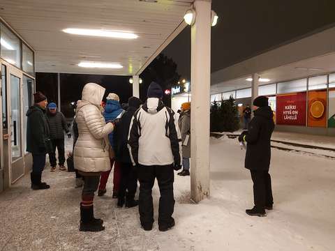 Pohjantorin ostoskeskuksen pihalla joukko ihmisiä talvivaatteissa ja hämärässä lumimaisemassa.