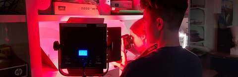 Henkilö on selkä kameraan päin ja katsoo edessä olevaa laitetta.