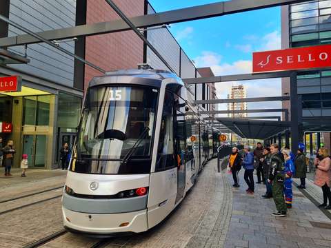 Raitiovaunu ja ihmisiä pysäkillä. Taustalla rakennuksia ja kauppakeskus Sellon kyltti.