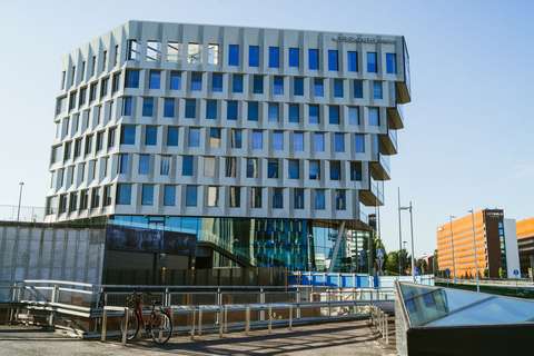 A light-coloured office building, the right side of which gradually widens from the bottom up.