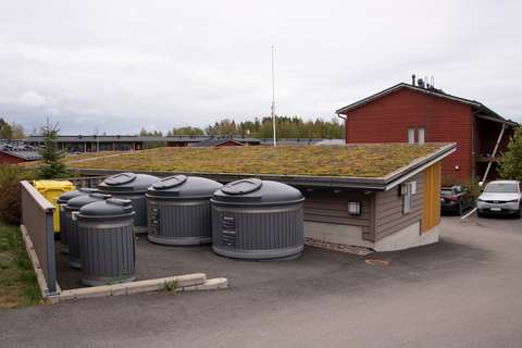 Waste and recycling bins behind a building.