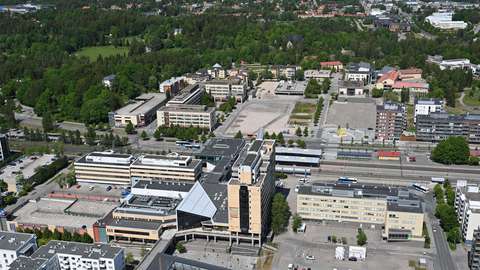 I mitten av bilden är Esbotorgets köpcentrum. Bakom det löper ett järnvägsspår, runt omkring finns flervåningshus och längre bort syns skog.