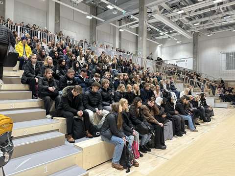 opiskelijat istuvat liikuntasalin katsomossa