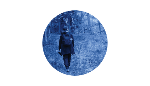 Henkilö kävelee metsässä ja katselee ympärilleen