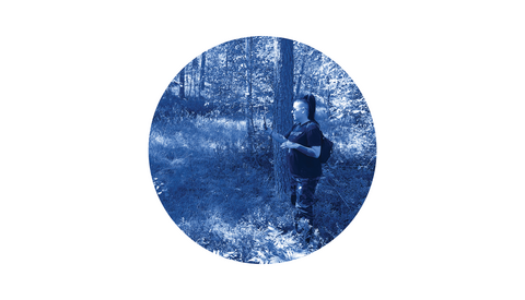 Henkilö seisoo metsässä ja kuvaa puhelimella luontoa.