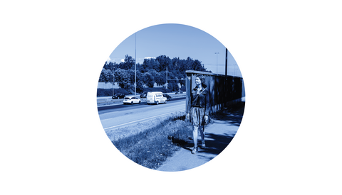 Henkilö kävelee jalankulkuväylällä lähellä autotietä ja meluaitaa.