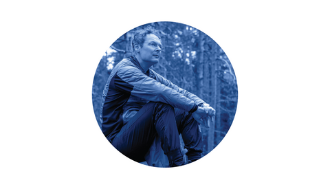 Henkilö istuu metsässä ja katselee ympärilleen.