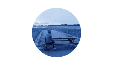 Henkilö istuu ruovikossa ulkoilupöydän äärellä ja katselee ympärilleen.