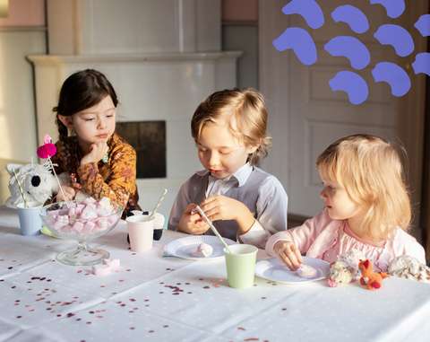 Kolme lasta pöydän ääressä vaahtokarkkeja lautasillaan.