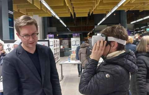 Kaksi ihmistä puolivartalokuvassa, toisella päässä virtuaalikypärä.