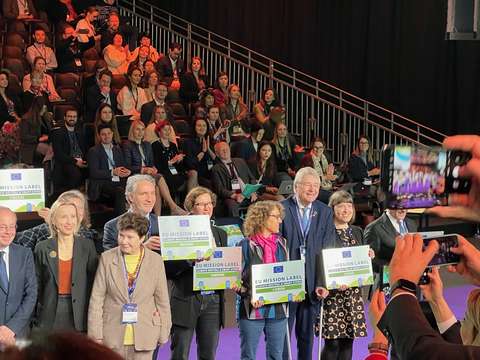 Yhteiskuva ihmisistä pitämässä tunnus-plakaattia.