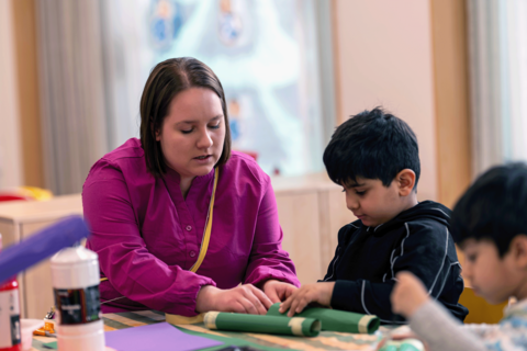 Läraren hjälper barnet med pyssel.