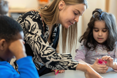 Opettaja ja lapset pelaavat yhdessä korttia.