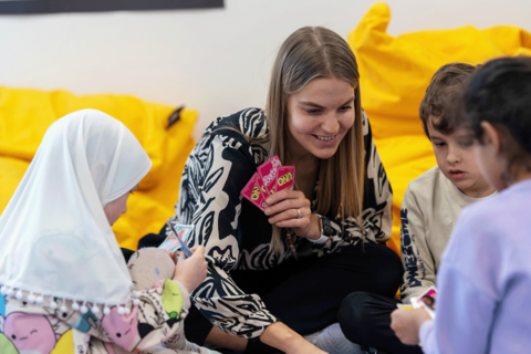 Opettaja pelaa korttia lasten kanssa.