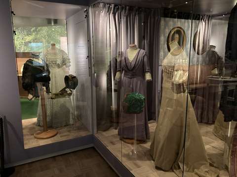 Sata vuotta vanhoja naisten leninkejä museon vitriinissä.